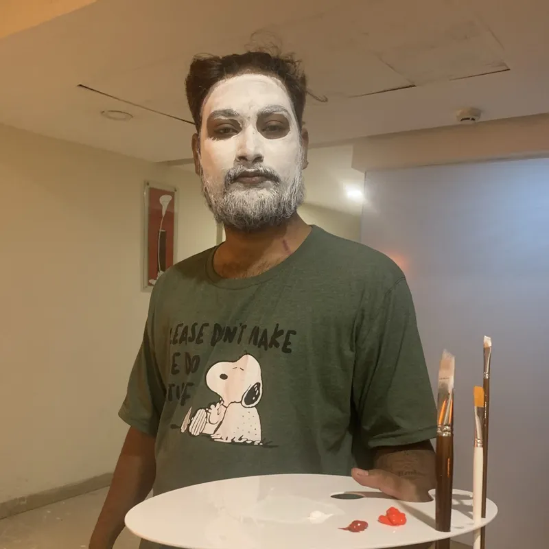 Ravi with white base paint holding a palette and brushes