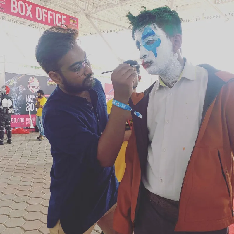 Ravi painting someone's face as Joker at a cosplay convention